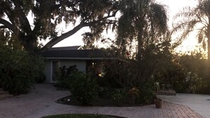 A residential property with a paved driveway, a lawn, and mature trees with hanging moss. - The Russell Lake House (Winter Haven)