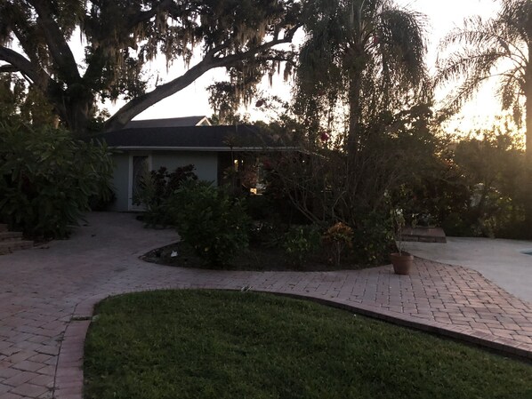 A residential property with a paved driveway, a lawn, and mature trees with hanging moss. - The Russell Lake House (Winter Haven)