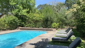Une piscine dotée d’une terrasse dallée et de chaises longues.