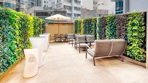 An indoor seating area with a green wall, white chairs, and a table with an umbrella.