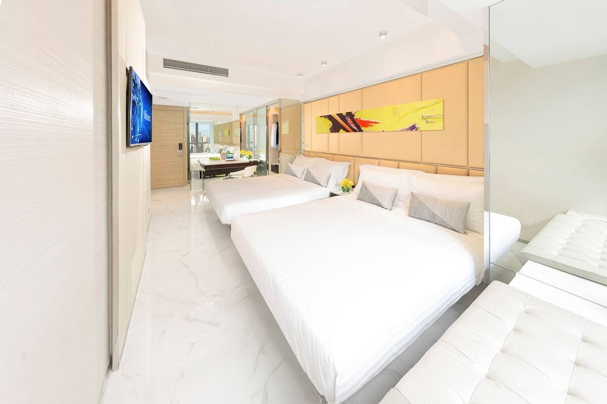 Una habitación de hotel moderna con una cama grande, una mesita de noche, un espejo y un televisor.