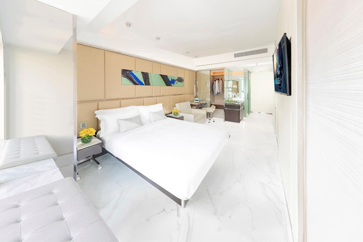 Una habitación de hotel moderna con una cama grande, un espacio de descanso, un tocador y una televisión.