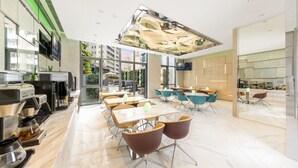 A modern cafe with marble flooring, multiple seating areas, and a large ceiling light fixture.