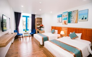 Une chambre d’hôtel avec deux lits, un bureau, une chaise, une télévision et des œuvres d’art accrochées aux murs.