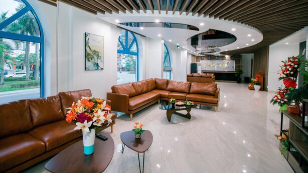 En moderne lobby med buet loft, lædersofaer og et sofabord med blomster.