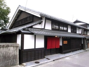 A traditional Japanese building with a tiled roof, wooden beams, and a red curtain. - Honmachi Juku (Hikone)