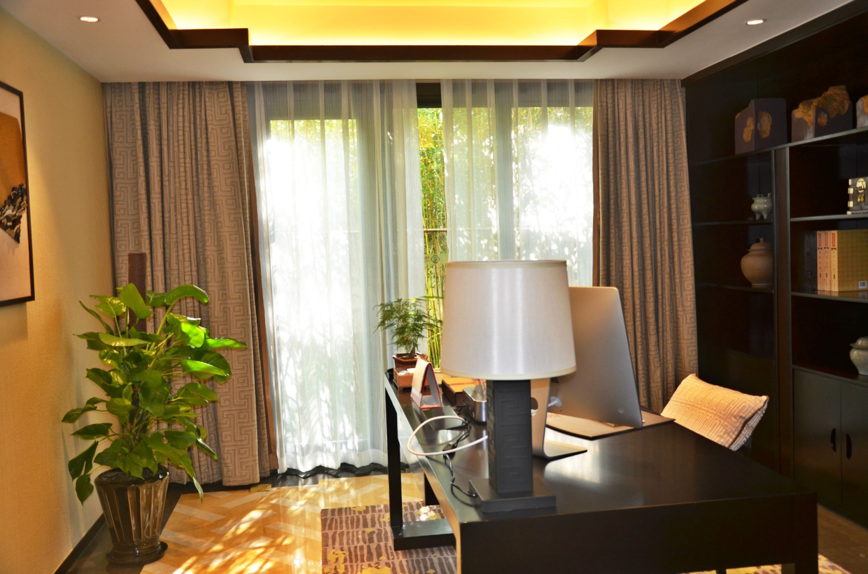 A modern room with a desk, chair, lamp, and a bookshelf.