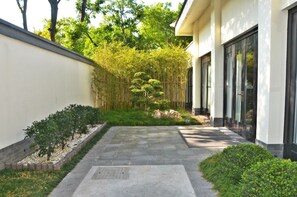 A pathway leading to a building with a bamboo garden and neatly trimmed bushes. - Slender West Lake Hot Spring Resort (Yangzhou)