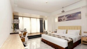 Una habitación de hotel moderna con una cama grande, un escritorio, una silla y un cuadro en la pared.