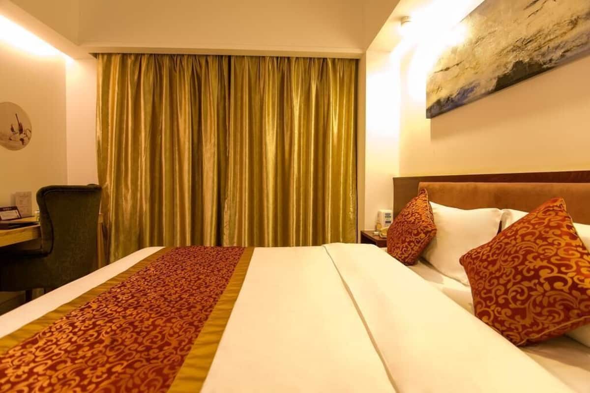 A hotel room with a bed, a desk, and a chair.