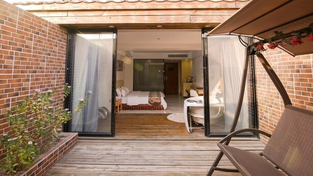 Un patio abierto que conduce a un dormitorio con una cama, una mesita y una silla.