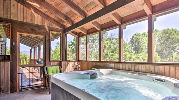 A wooden cabin with a hot tub, a deck, and large windows offering a view of the forest. - Idyllic Sevierville Cabin: Deck + Smoky Mtn View! (Sevierville)