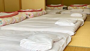Habitación de hotel con varias camas, cada una con ropa blanca y mantas coloridas.