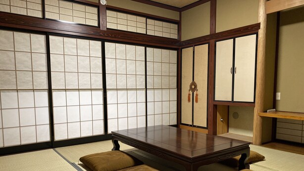 Una habitación con esteras de tatami, una mesa de madera baja y cojines.