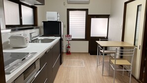 Una cocina compacta equipada con microondas, tostadora y pileta. Hay un extintor de incendios colgado en la pared y una ventana con persianas.