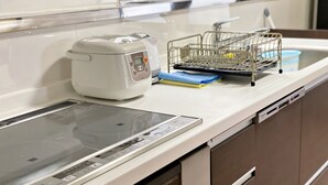 Una cocina moderna con horno empotrado, lavavajillas y una pequeña isla central con hervidor y escurreplatos.