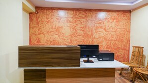 A reception desk with a computer, a wooden counter, and a chair. - OYO 63371 R Square Stay (Hyderabad)