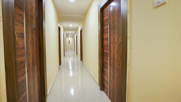 A long, narrow hallway with wooden doors on both sides and a tiled floor. - OYO 63371 R Square Stay (Hyderabad)