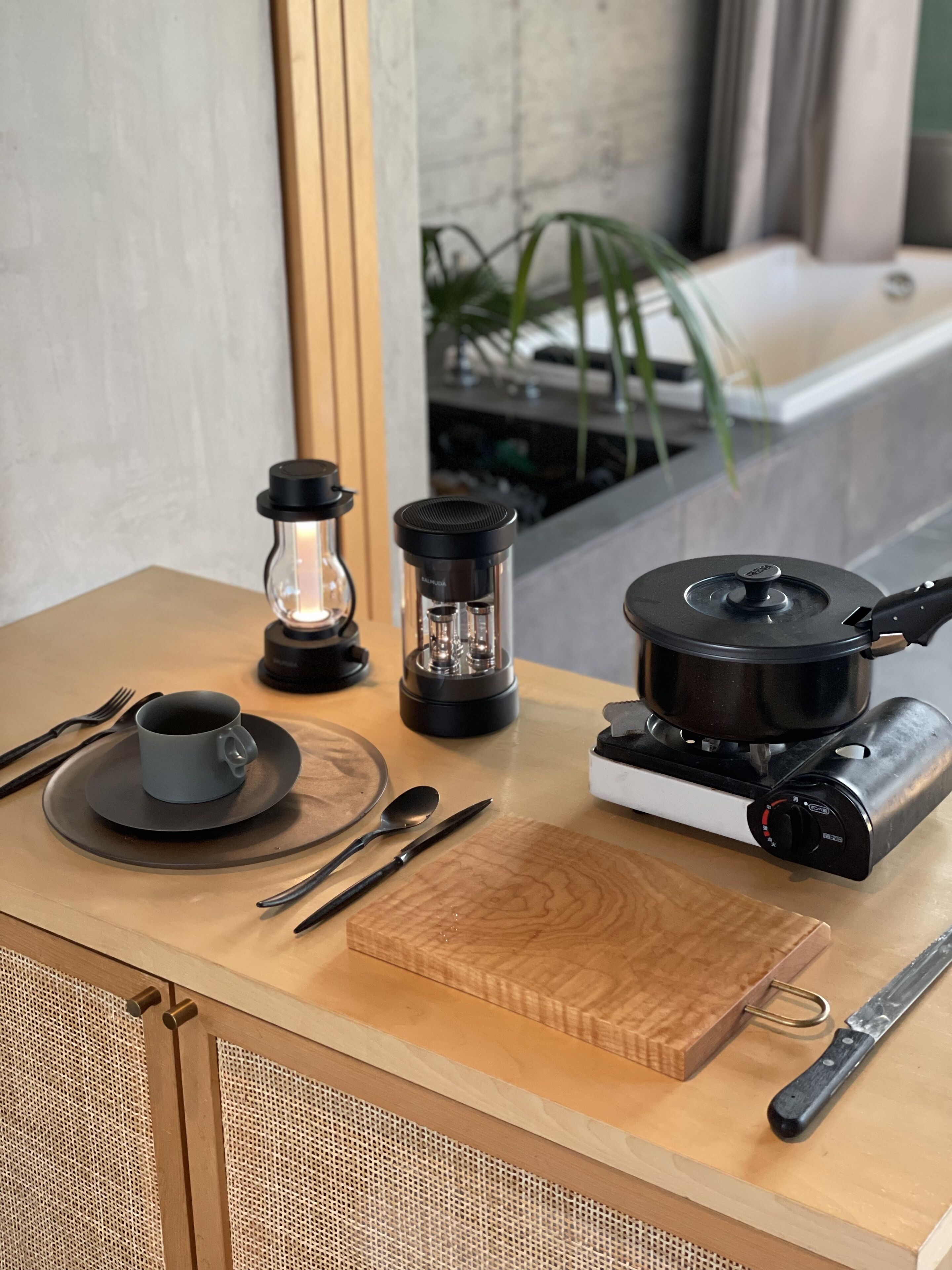 Una encimera de cocina con cafetera, hervidor, taza y cubiertos.