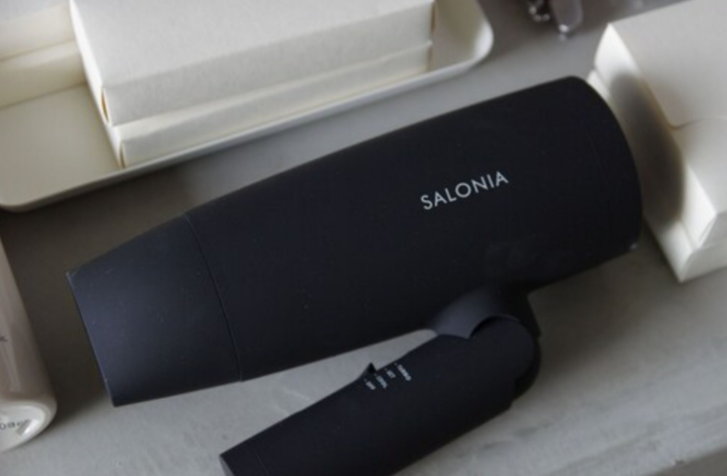 A black box with the word "SALONIA" on it, placed on a table with other white boxes.