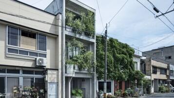 Un edificio moderno de dos pisos con un balcón en el nivel superior, rodeado de otras edificaciones residenciales.