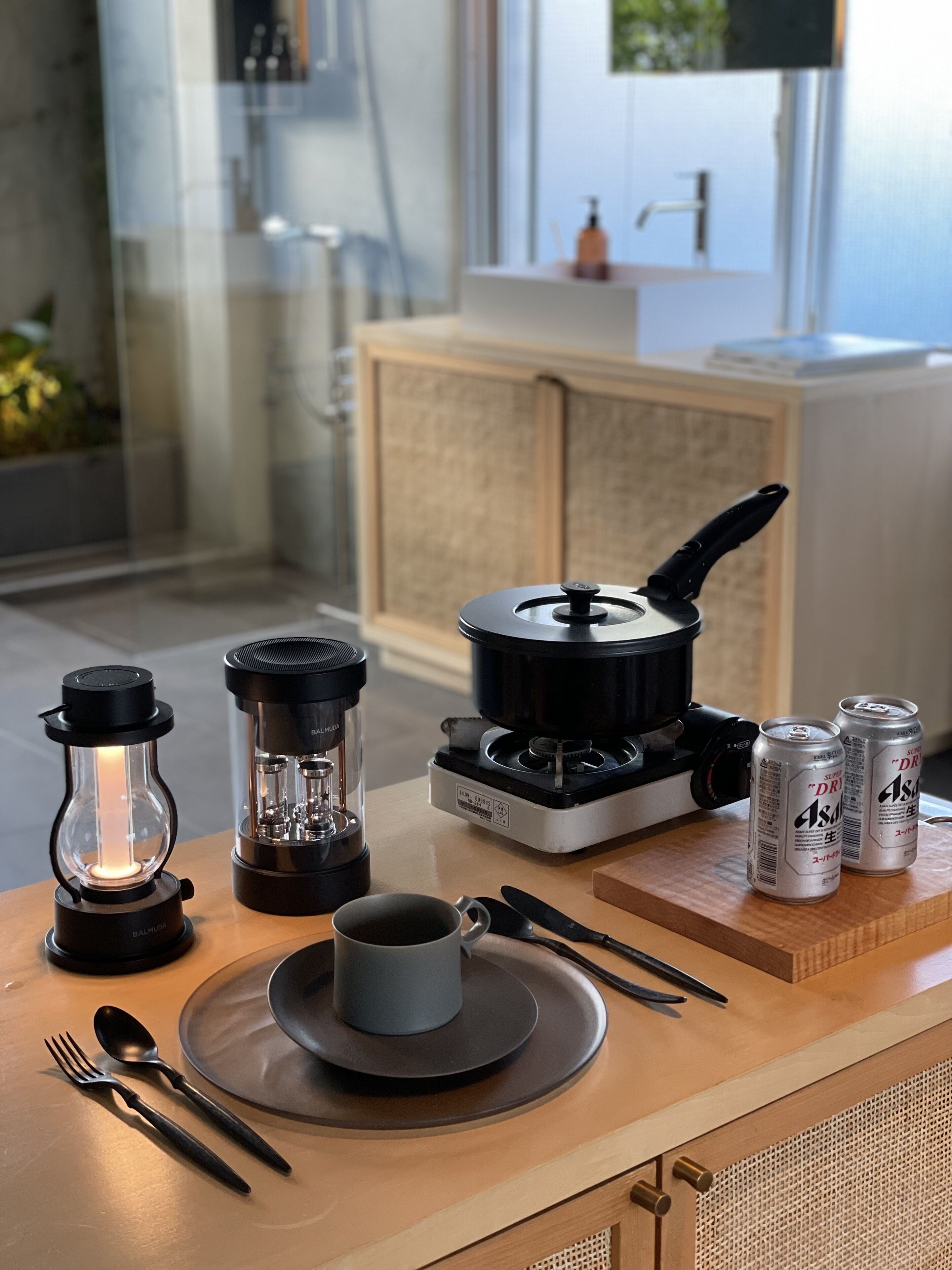 A kitchen with a stove, a kettle, a lantern, a cup, and a plate with cutlery.