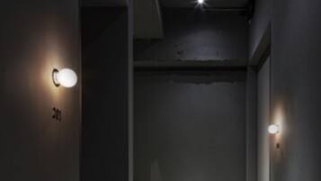 A narrow, dimly lit hallway with two wall-mounted light fixtures and a visible door at the end.