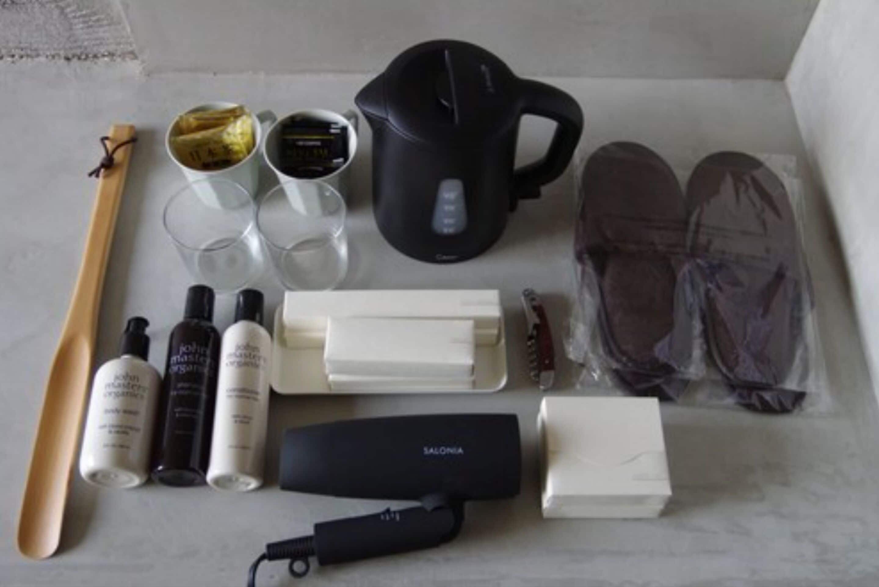 A neatly arranged set of toiletries and a kettle on a marble surface.