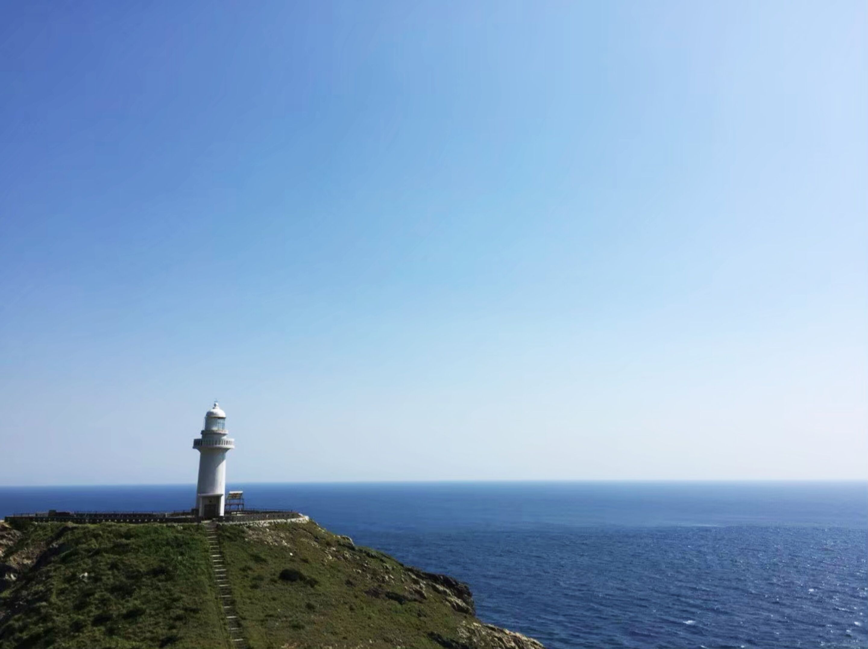 Un faro sobre un risco cubierto de hierba con vistas al océano.
