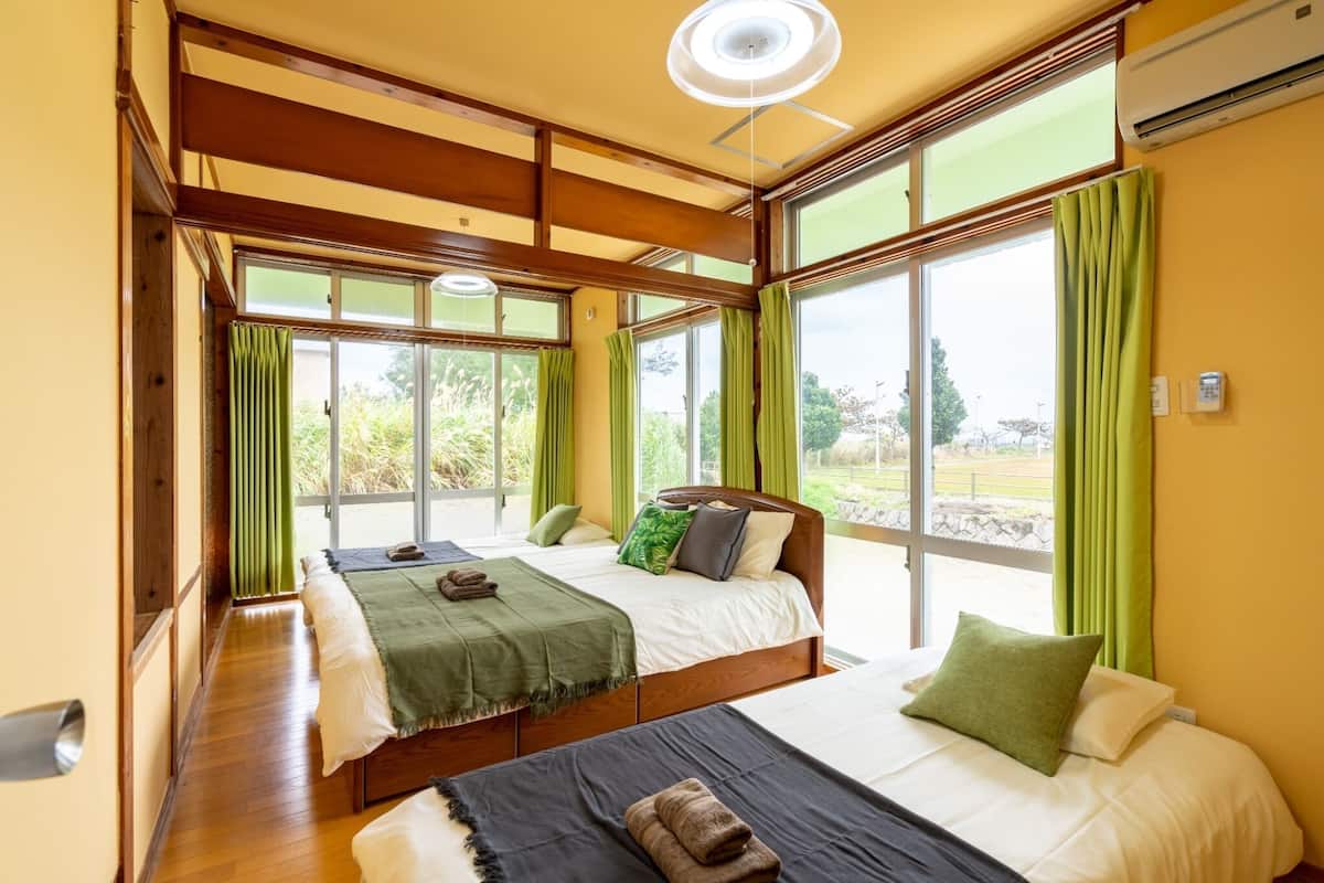 Een hotelkamer met twee bedden, grote ramen en uitzicht op de omgeving.