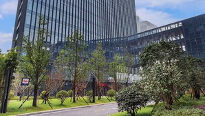 A modern high-rise building with a glass facade, surrounded by greenery and a clear sky. - Lily's Hotel Hangzhou (Hangzhou)