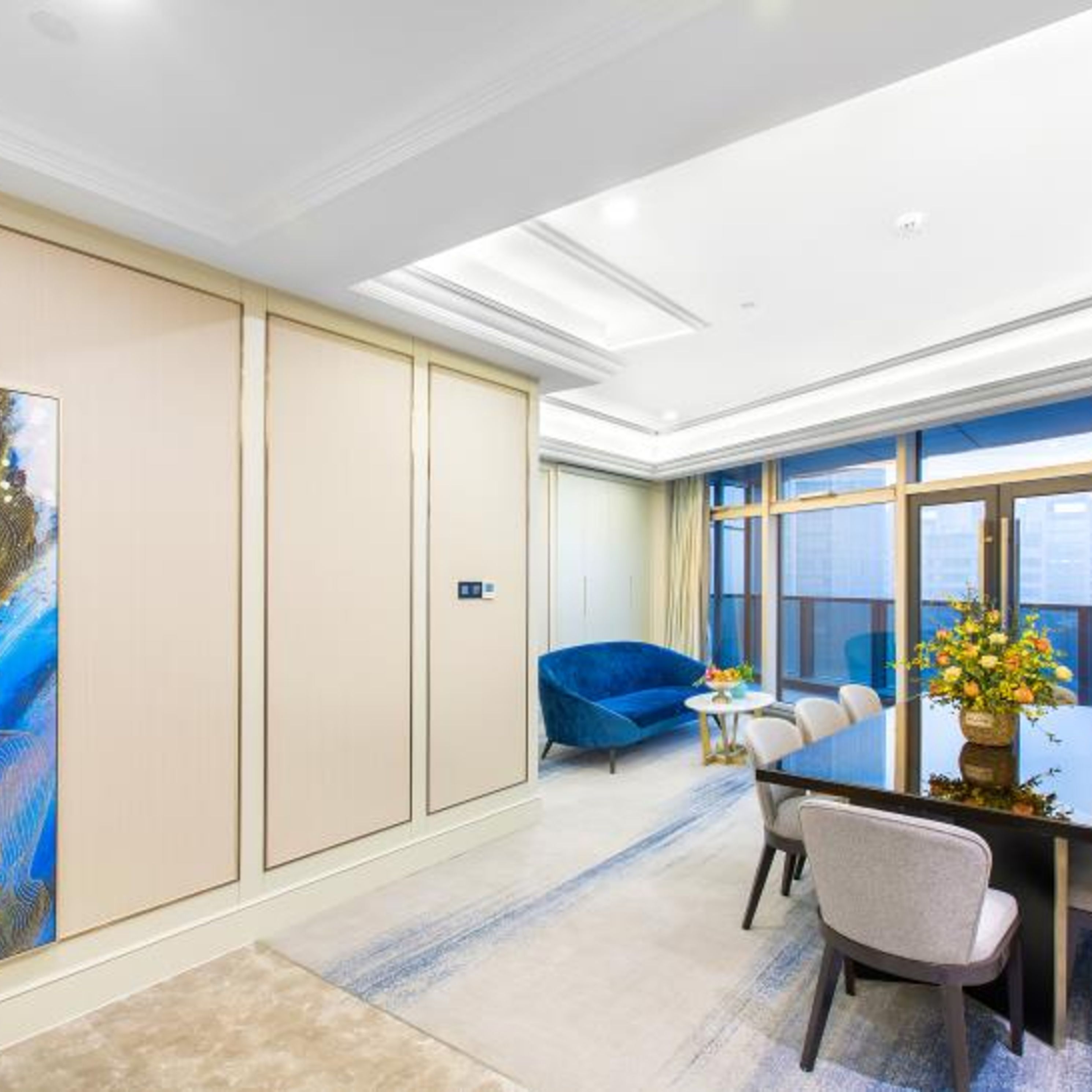 A modern conference room with a glass table, blue sofa, and a large window.