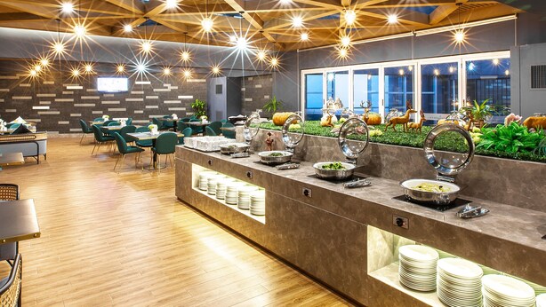 A modern dining area with a long counter, multiple seating arrangements, and a ceiling with geometric wooden beams and hanging lights. - Lily's Hotel Hangzhou (Hangzhou)