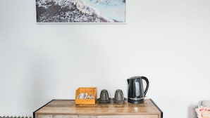 A wooden table with a radiator, a box of slippers, two cups, and a kettle. - College Lawn Hotel - Hostel (Prahran)