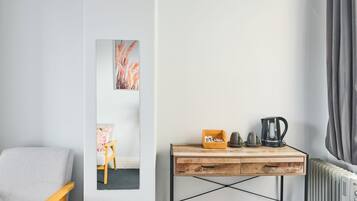 Una habitación con un escritorio de madera, una silla, un radiador y una obra de arte en la pared.