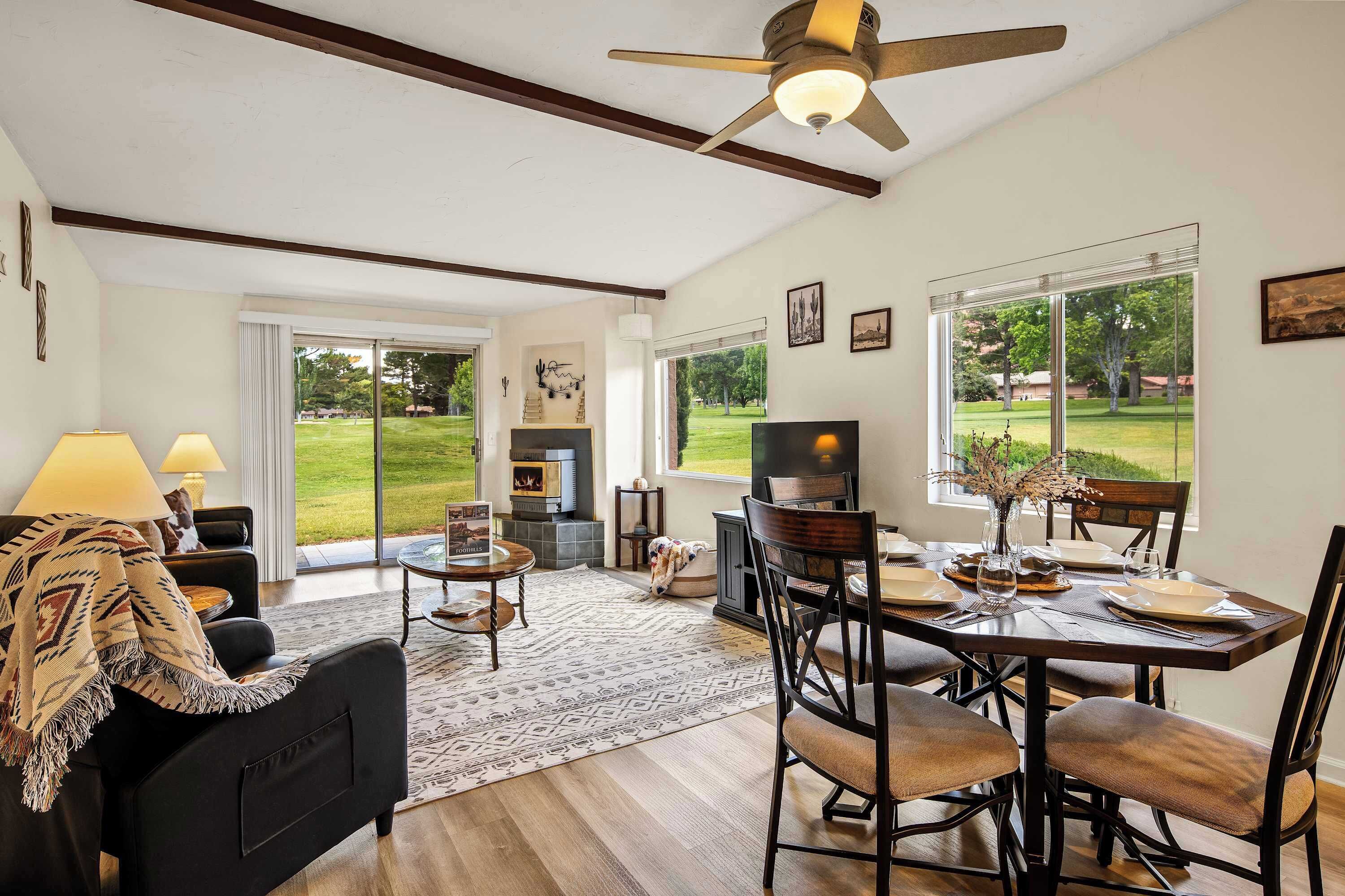 A dining area with a table set for four, a fireplace, and a view of the outdoors.