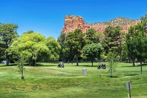 A golf course with a prominent red rock formation in the background.
