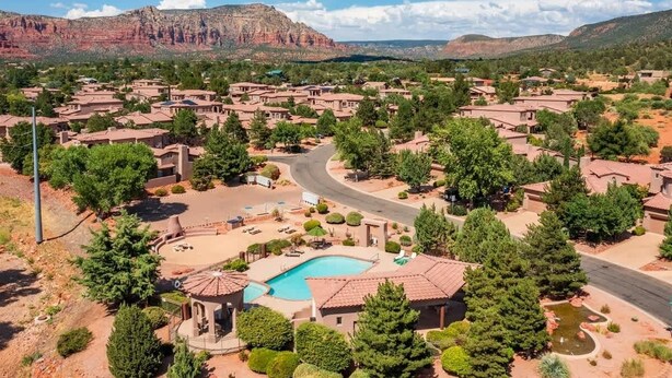 Un quartier résidentiel avec des maisons, une piscine et une vue sur les montagnes en arrière-plan.