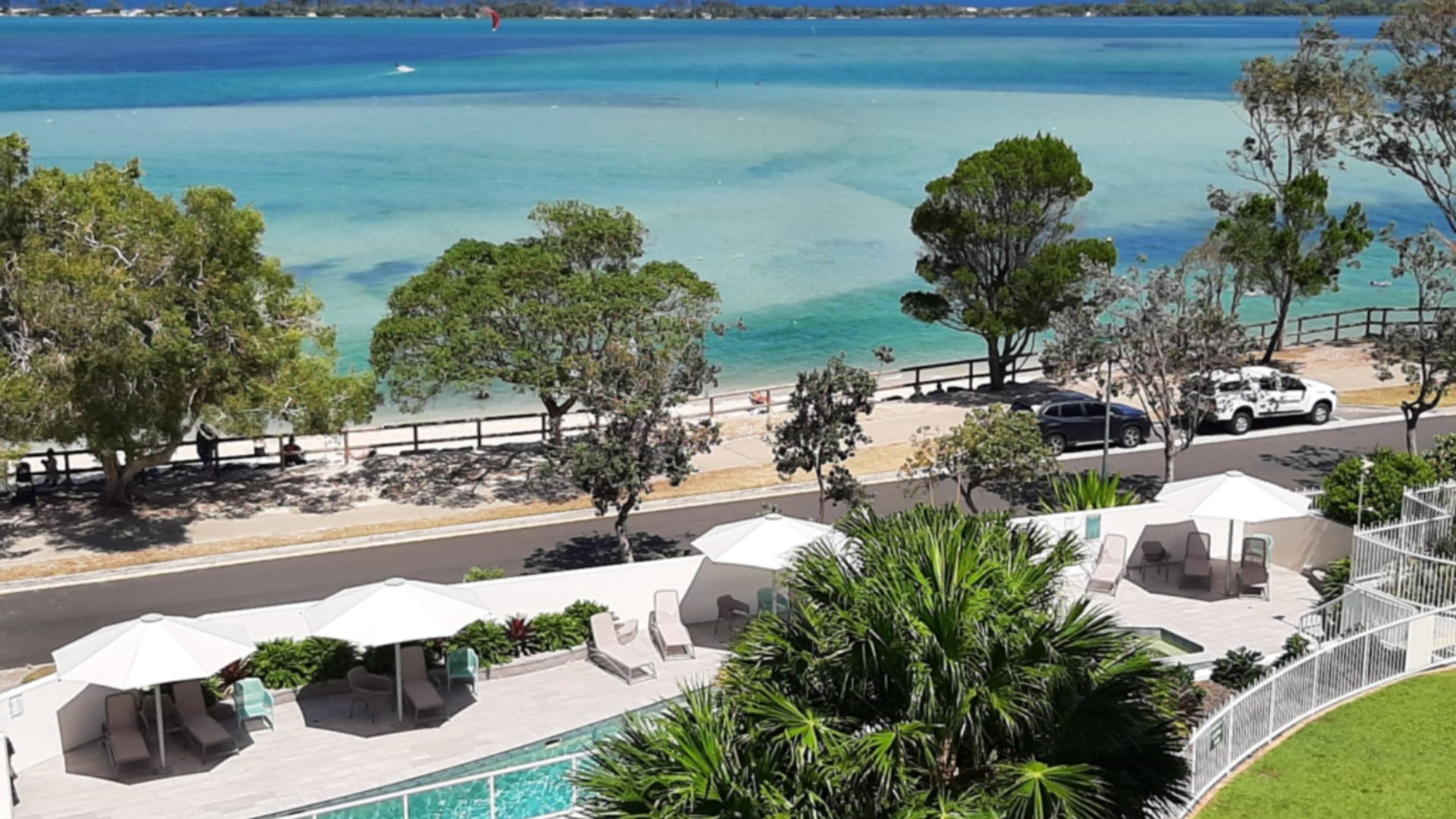 Una proprietà fronte spiaggia con piscina, lettini e ombrelloni.