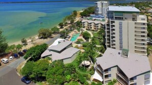 A coastal hotel with multiple buildings, a swimming pool, and a beach.