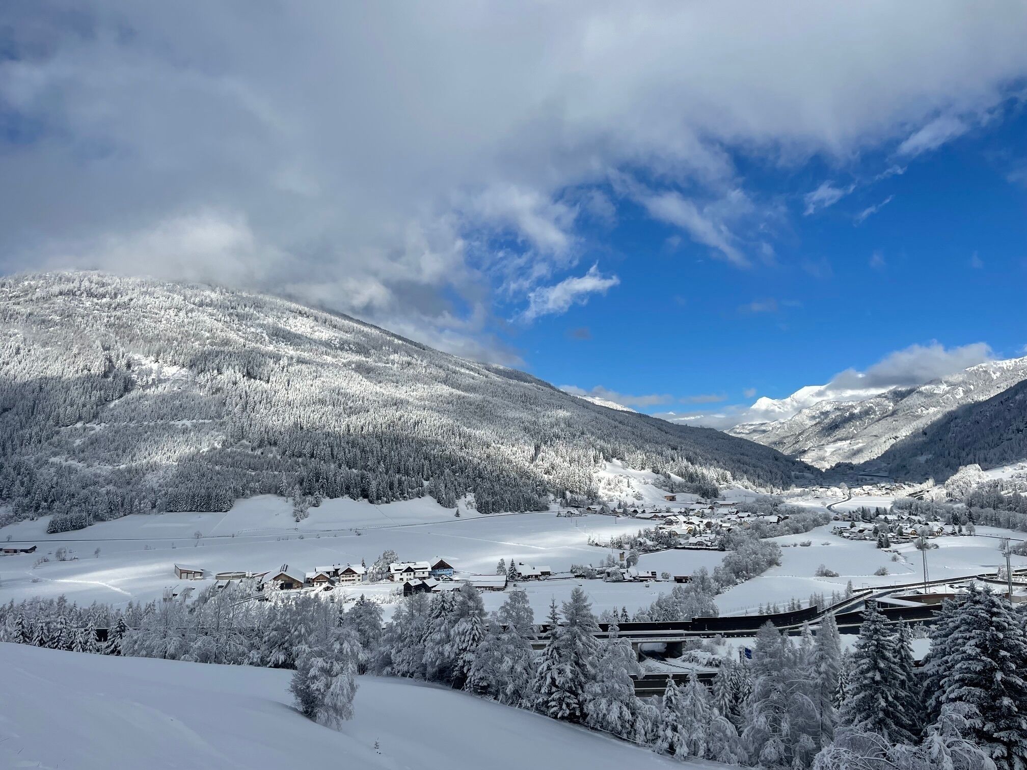 Un paisaje monta ñoso cubierto de nieve con un pequeño pueblo y casas.