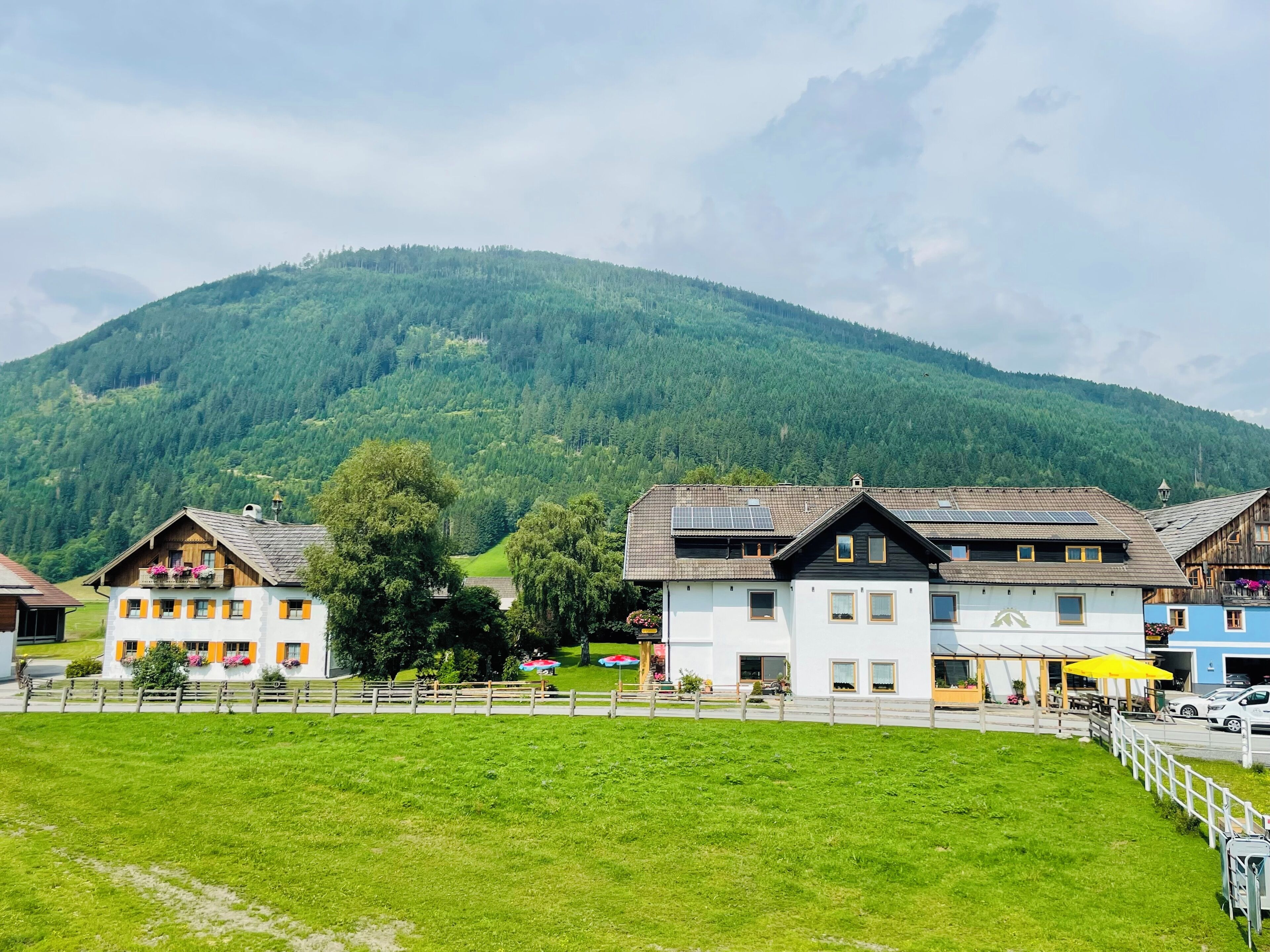 Een rij traditionele gebouwen in Europese stijl, met schuine daken, zonnepanelen en een berg op de achtergrond.