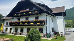 Un chalet traditionnel doté d’un balcon orné de fleurs, d’une terrasse avec des meubles d’extérieur et offrant une vue sur le paysage environnant.
