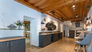 Une cuisine moderne avec des poutres en bois, un coin repas et une moto accrochée au mur.