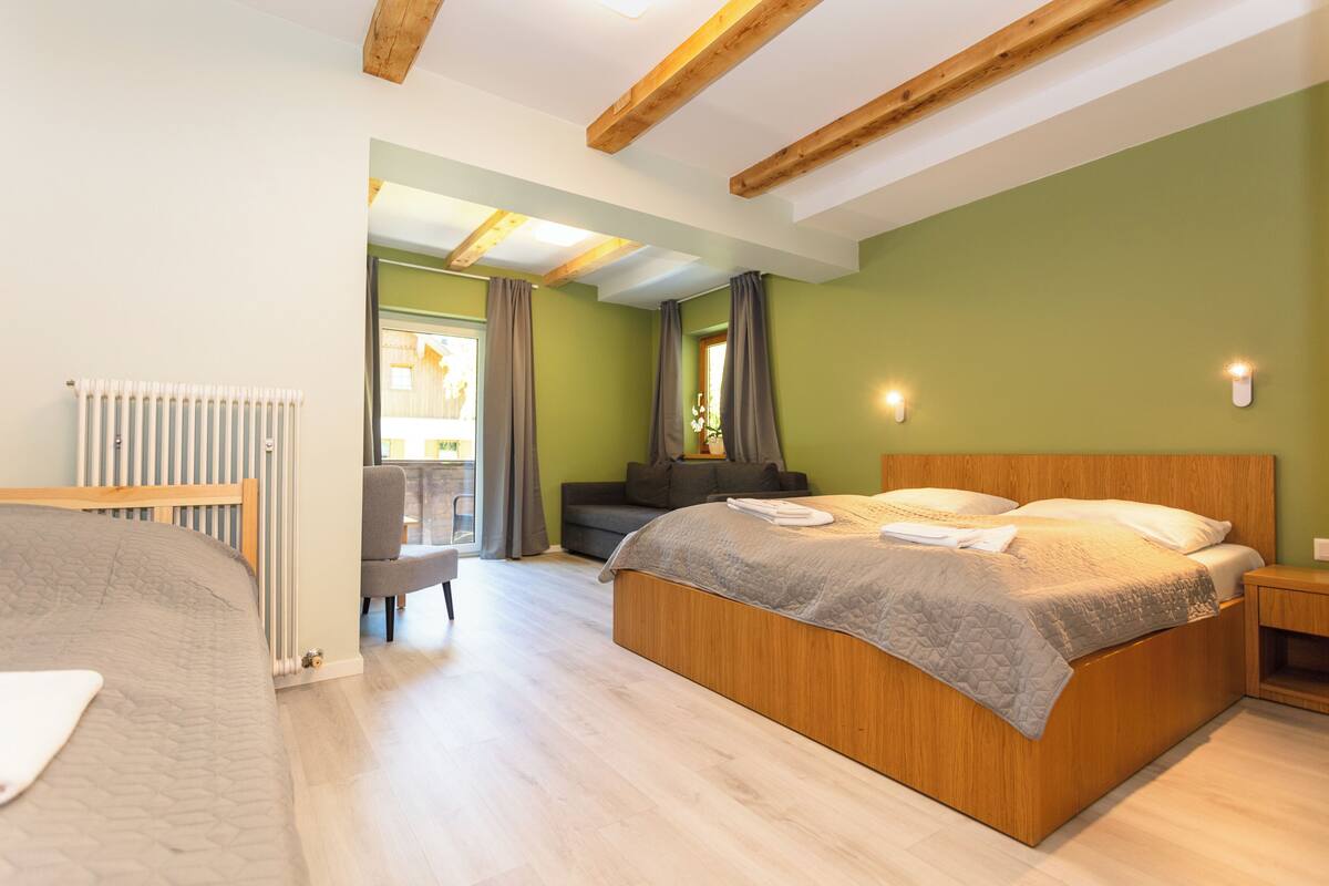 A bedroom with a wooden bed, a radiator, a grey sofa, and a small table.