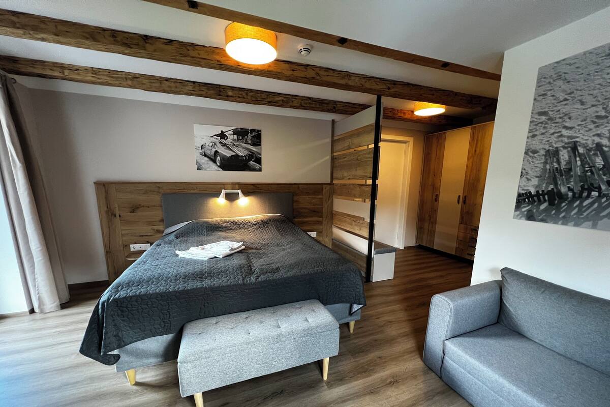 A modern bedroom with a bed, bench, and sofa.