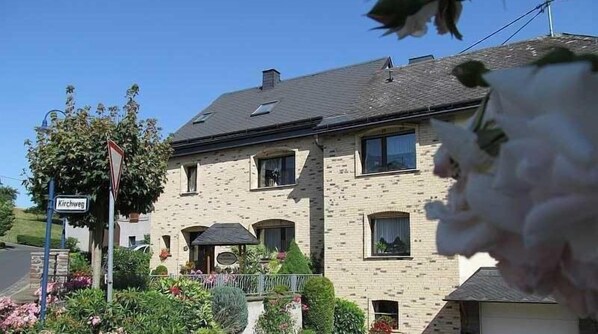 Stunning two-story home with a brick facade and a pitched roof, featuring a bay window and a charming garden.