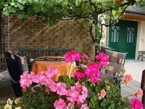 Relax in a charming outdoor seating area surrounded by vibrant flowers and a rustic brick wall.