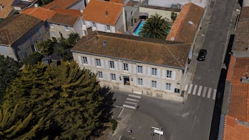 A hotel with a tiled roof, a swimming pool, and a crosswalk in front.