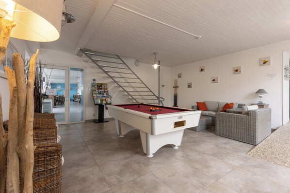 A pool table in a room with a staircase, a sofa, and a lamp. - Hotel Le Square (Saint-Pierre-d'Oleron)